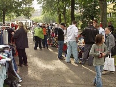 Der Flohmarkt der Rotenburger Werke mit vielen Besuchern, die bei Sonnenschein unter Bäumen an Tischen entlangflanieren