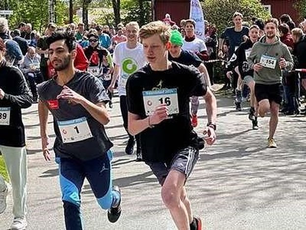 Eine Gruppe junger, gut gelaunter Menschen sitzt im Freien nebeneinander 
